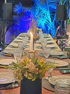 a long table with a candle and plates and glasses at Portal Das Fadas - Hospedagem in Cavalcante