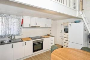 a kitchen with white cabinets and a wooden table at Beachfront 1BR Loft. Surf-Café-Unwind in Marcoola +10 photos