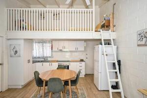 a kitchen with a table and chairs and a loft at Beachfront 1BR Loft. Surf-Café-Unwind in Marcoola