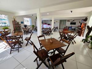 an empty restaurant with wooden tables and chairs at Pousada Sol Nascente in Guaibim +19 photos