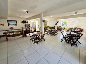 a room with tables and chairs and a pool table at Pousada Sol Nascente in Guaibim
