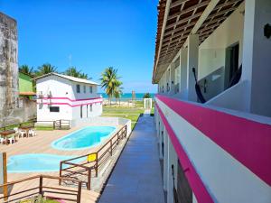 a house with a swimming pool and a balcony at Pousada Sol Nascente in Guaibim