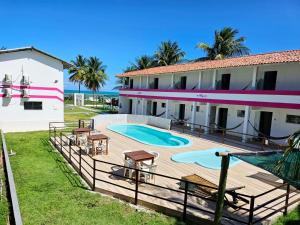 a resort with a swimming pool and a building at Pousada Sol Nascente in Guaibim
