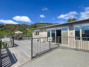 a building with a fence and a table on a deck at Selwyn Heights in Akaroa