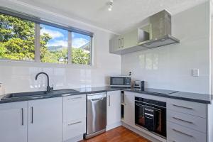 a white kitchen with a sink and a microwave at Selwyn Heights in Akaroa