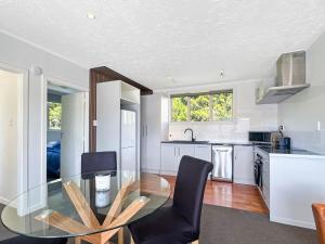 a kitchen with a glass table and black chairs at Selwyn Heights in Akaroa +12 photos
