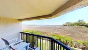 a balcony with two chairs and a view of a field at 240 Captains Quarters in Hilton Head Island