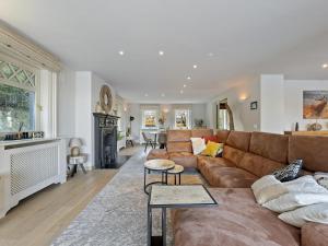 a living room with a brown couch and a fireplace at Luxury Country House with Pool in Manhay