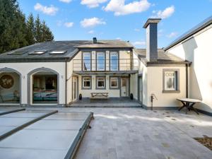 an exterior view of a house with a patio at Luxury Country House with Pool in Manhay
