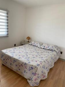 a bedroom with a bed with a floral comforter at Cabañas CR guanaqueros in Coquimbo