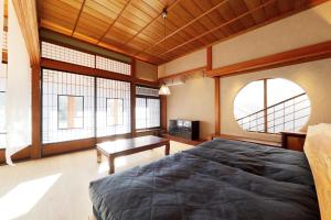 a bedroom with a bed and a table and windows at YASUYA-yasuya- in Yasugi