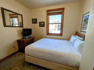 a bedroom with a white bed and a television at Antlers Gulch 501 by SummitCove Lodging in Colorado in Keystone