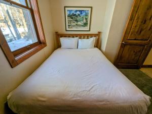 a small bedroom with a white bed with a window at Antlers Gulch 501 by SummitCove Lodging in Colorado in Keystone