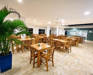 a restaurant with wooden tables and chairs and plants at Hotel Playarena in Coveñas