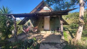 a small green house with a white door at Vila Druida Spa Caipira in São Thomé das Letras