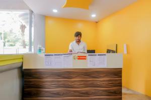 a man standing behind a counter in an office at Hotel O Rest Inn in Yeraoda