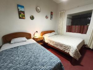 a bedroom with two beds and a window at Casa El Capulí in Cajamarca