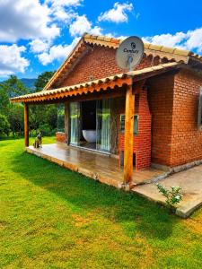 a small brick house with a dog sitting on a deck at Chalé Água Santa in São Thomé das Letras
