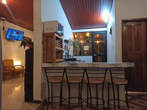 a bar in a kitchen with three stools at Home Capybara Stay in Mindo