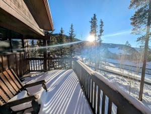 a snow covered deck with a bench on a porch at Trappers Crossing 8753 by SummitCove Lodging in Colorado in Keystone