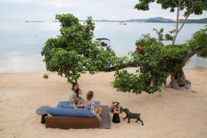 two women sitting on a couch on the beach at Clay Beach Samui - Beachfront Villas in Bophut
