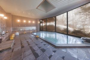 a swimming pool in a building with a large window at Club Wyndham Shirakabaso Shigakogen in Yamanouchi