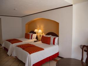 a hotel room with two beds with red and white sheets at Hotel Misión Comanjilla in Comanjilla +32 photos