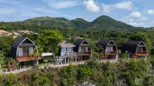 a row of huts on a hill with mountains in the background at Eco-tourist Dream Beach Cliff Villas in Nusa Penida