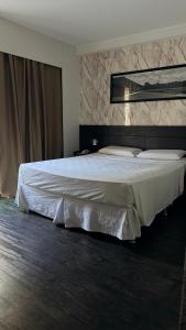 a bedroom with a large white bed with a mirror at Flat Suites Pampulha - AP 122 - Particular in Belo Horizonte +15 photos