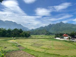 a green field with mountains in the background at MAI CHAU inn in Mai Châu