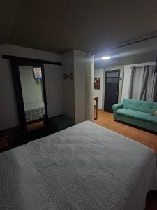 a bedroom with a bed and a blue couch at Hospedaje El Rancho in Castillos