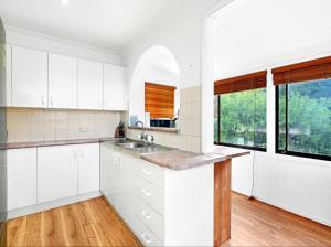 a white kitchen with white cabinets and a sink at Tranquil Waters Edge Escape in Sanctuary Point