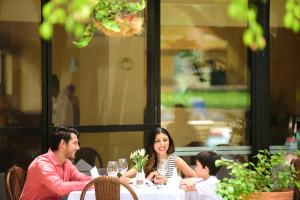 a woman and a man sitting at a table with a child at Hotel Misión Comanjilla in Comanjilla