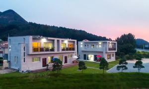 a large building in a field with a mountain at Chuncheon Venue Pool Villa August 19 in Chuncheon