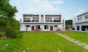 a large white house with a lawn in front of it at Chuncheon Venue Pool Villa August 19 in Chuncheon