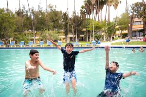 three young boys playing in a swimming pool at Hotel Misión Comanjilla in Comanjilla