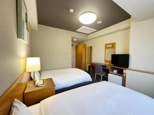 a hotel room with two beds and a desk at Hotel Route-Inn Tajimi Inter in Tajimi