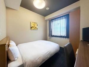 a small room with a bed and a window at Hotel Route-Inn Tajimi Inter in Tajimi