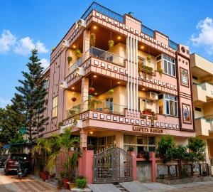 a tall pink building with potted plants on it at Kasotiya Mansion Homestay in Surūrnagar