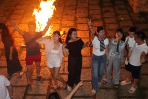 a group of people standing around in front of a fire at ANOR Farmstay - Two Double Bed in Hue