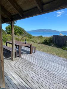 a wooden deck with a picnic table and the ocean at Beach side Waikanae Bach in Waikanae