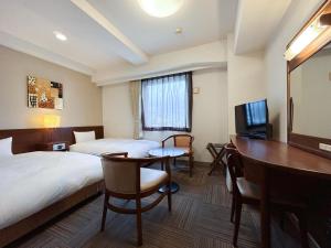 a hotel room with two beds and a desk at Hotel Route-Inn Nobeoka Ekimae in Nobeoka