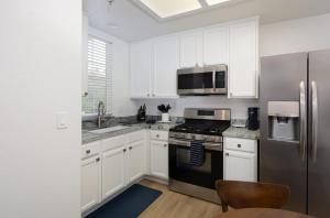 a kitchen with white cabinets and a stainless steel refrigerator at Luxury At Pier Avenue in Oceano