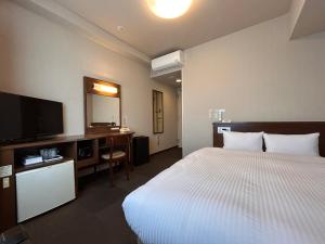 a hotel room with a bed and a flat screen tv at Hotel Route-Inn Nobeoka Ekimae in Nobeoka +50 photos