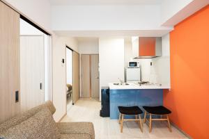 an orange and white kitchen with two chairs and a counter at SPAZIO 4 Tenjin Minami in Fukuoka