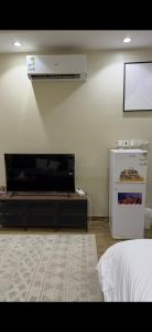 a living room with a television and a small refrigerator at شقق تاج اليرموك الفندقية in Tabuk