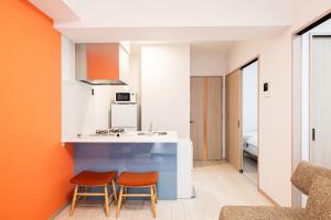 a kitchen with two chairs and a counter with an orange wall at SPAZIO 4 Tenjin Minami in Fukuoka