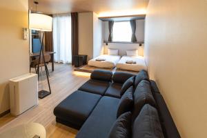 a living room with a couch and a bed at ReLA Kashiwa Eki Nishi in Kashiwa