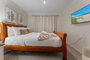 a bedroom with a bed with white sheets and pillows at Flannel Flower Beach House in Shoal Bay