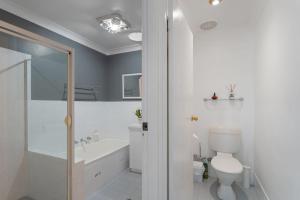a bathroom with a toilet and a tub and a sink at Flannel Flower Beach House in Shoal Bay +24 photos